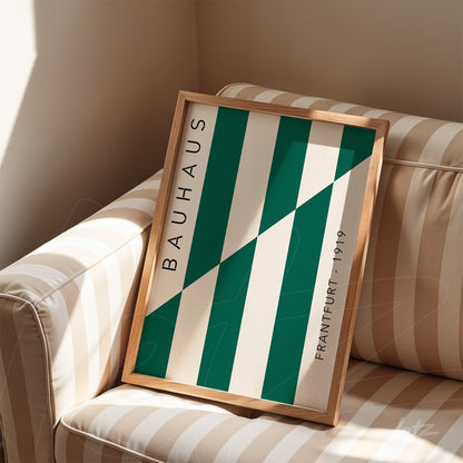 bauhaus style art print in light wood frame displayed on a beige and white striped sofa