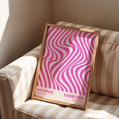 poster with vibrant pink and beige wave art in wooden frame on striped sofa