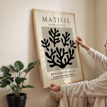 decorative framed art featuring matisse's cut-outs with black organic shapes on a light background, framed in light wood