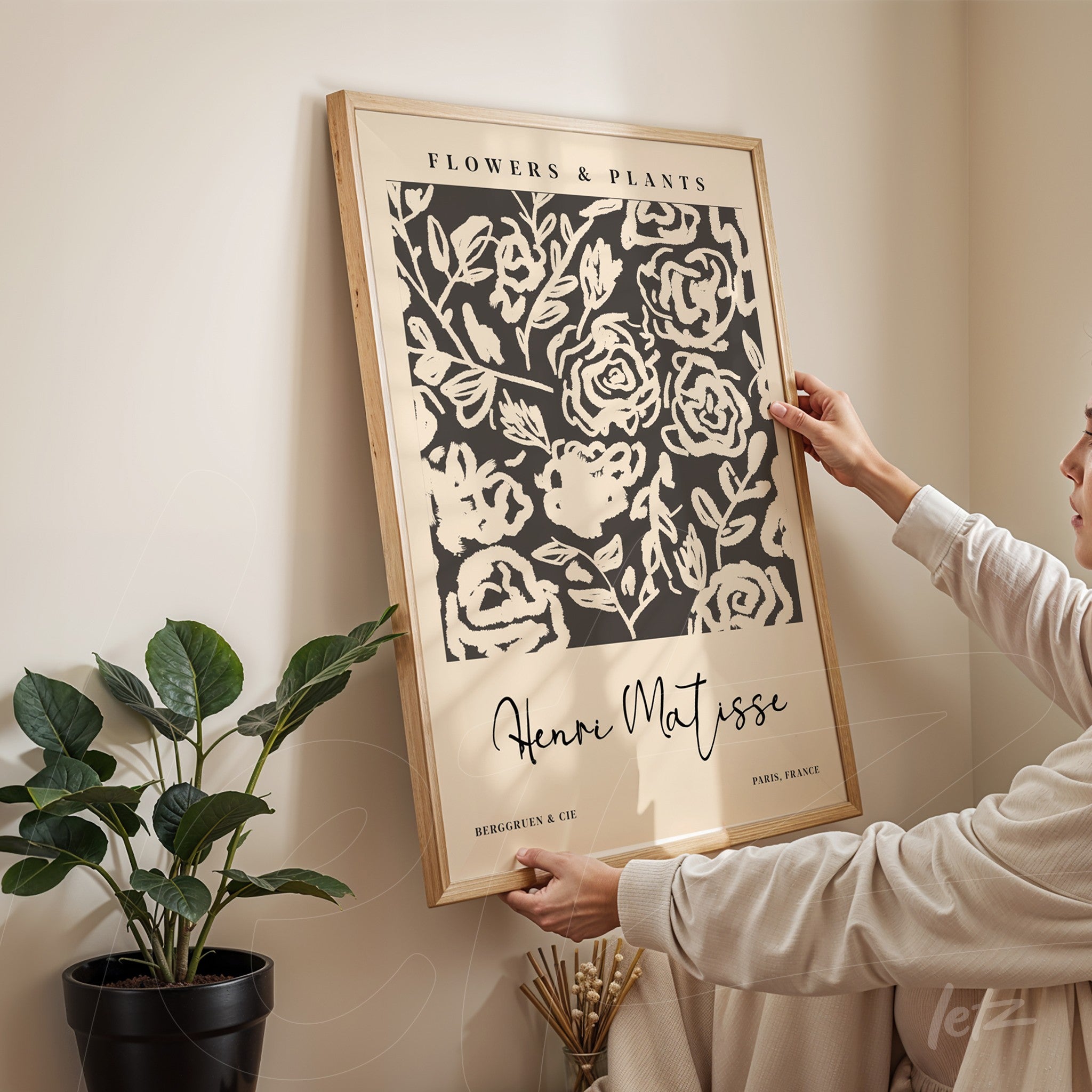 decorative wall art featuring stylized flowers on a black background with a light wood frame, held by a person in an indoor setting
