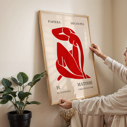 framed modern art piece featuring a female figure in red tones with classic font text displayed in a bright space with natural light