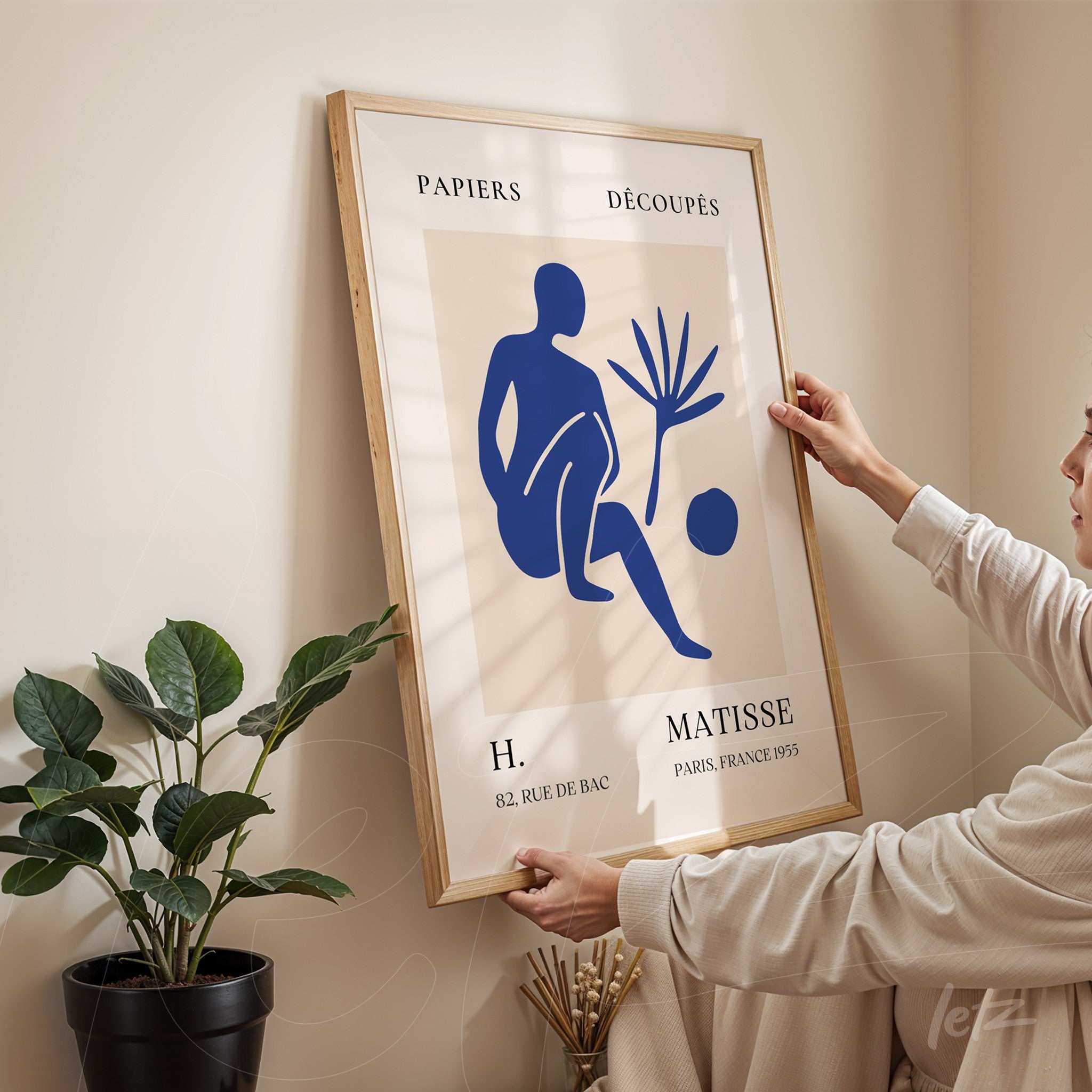 framed art piece featuring a stylized blue figure on a light background with a light wood frame
