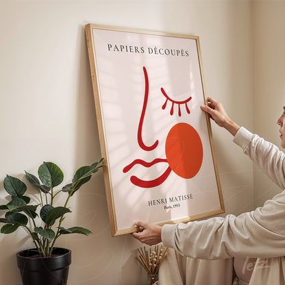 framed art print by Henri Matisse titled Papiers Découpés displayed in light wooden frame in a bright interior