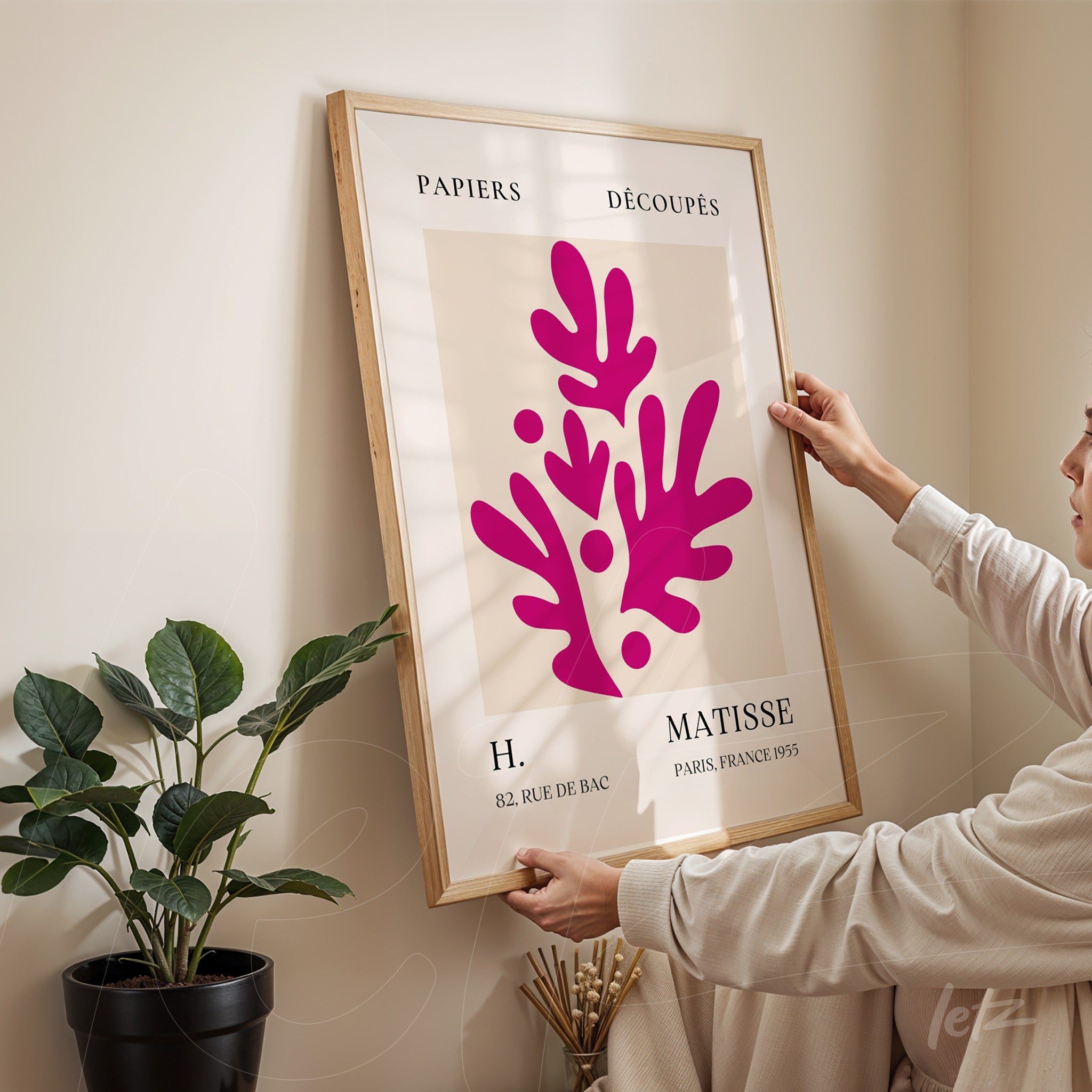 framed modern art print with vibrant pink organic shapes on a light background in a light wood frame