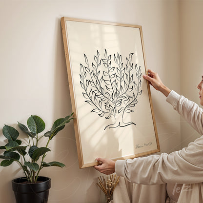 framed minimalist illustration of a tree in light wood frame held by a person in a neutral setting