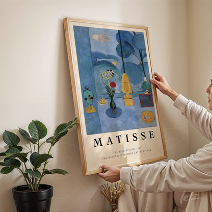 framed artwork by Matisse titled 'The Blue Period' in a light wood frame, featuring pastel colors and surrounded by plants