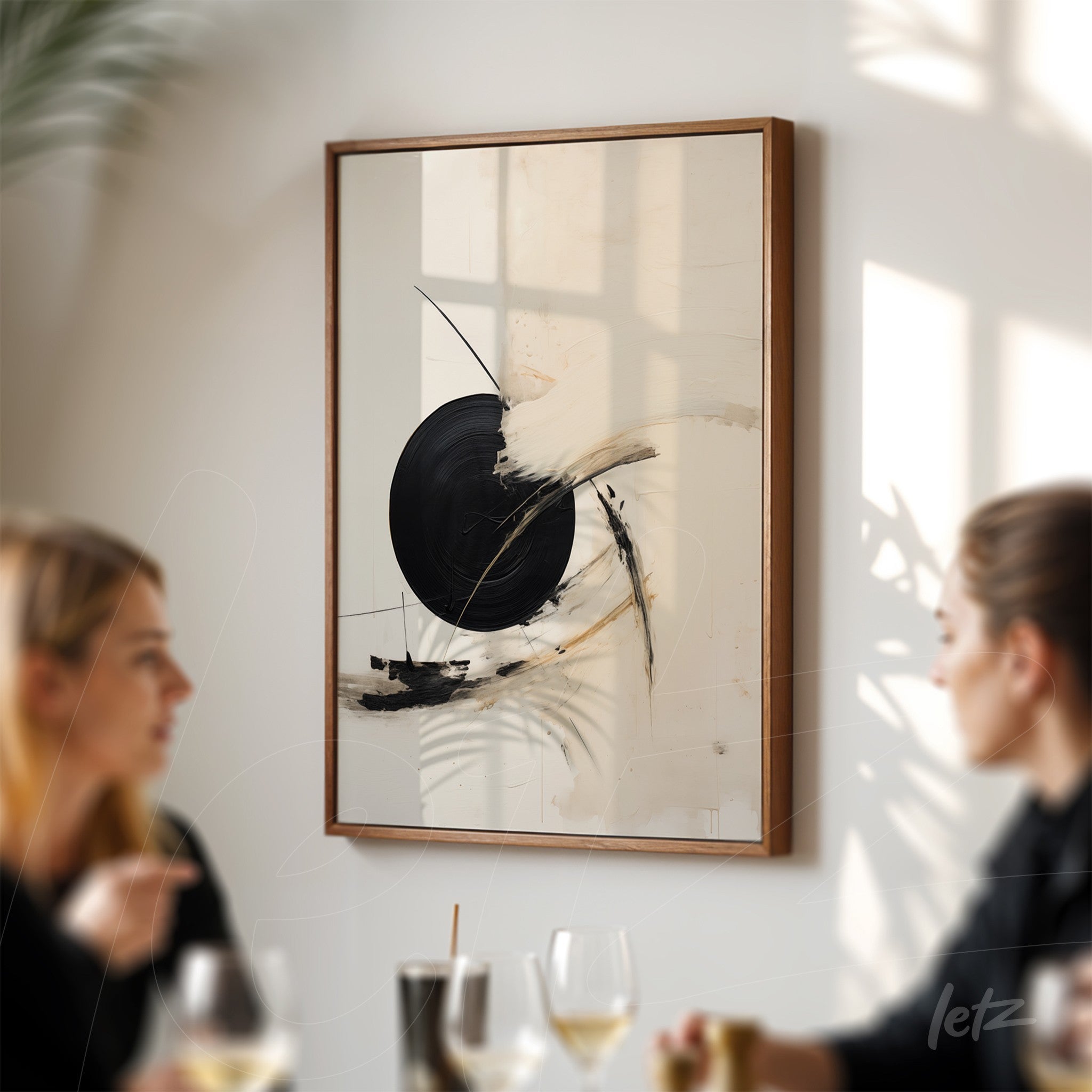 abstract artwork featuring black circular shapes on a light background, framed with a light wood frame, displayed on a well-lit wall