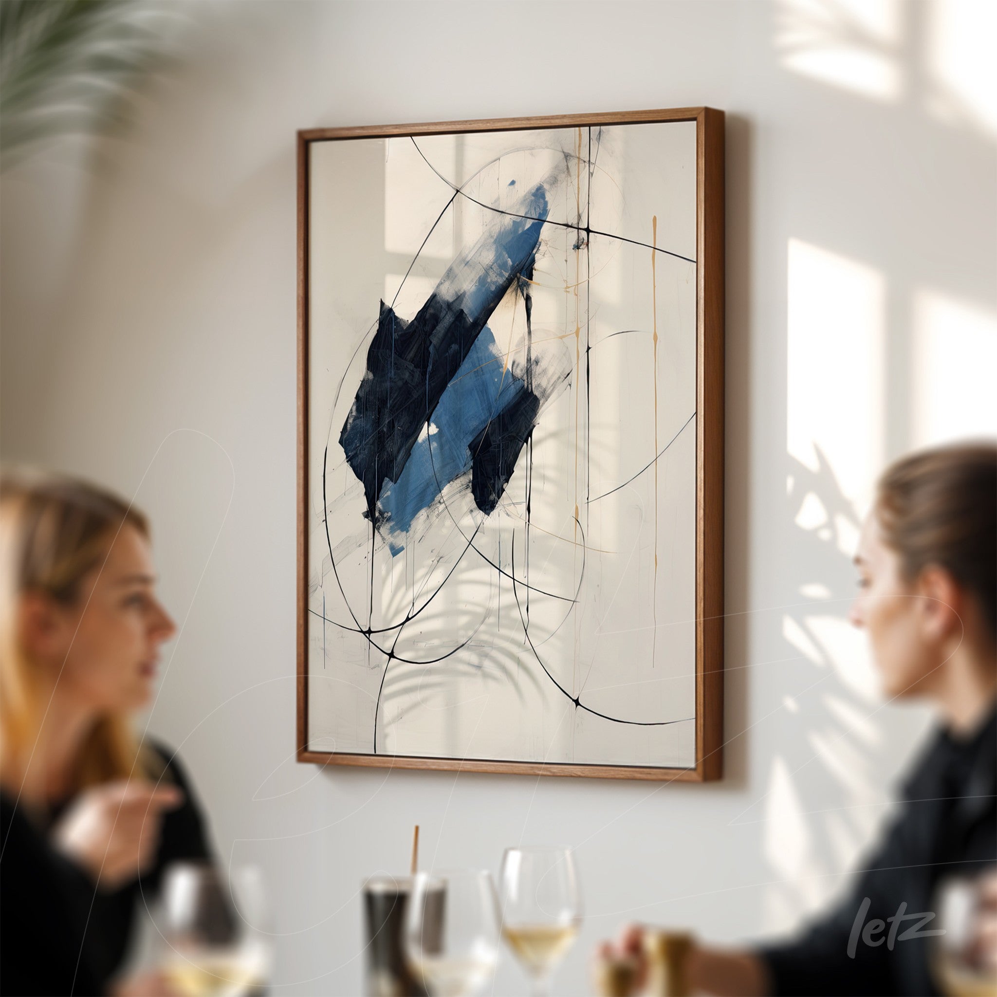 abstract wall art with dominant blue hues and curved lines in a dark wooden frame displayed on a wall with two people in the foreground