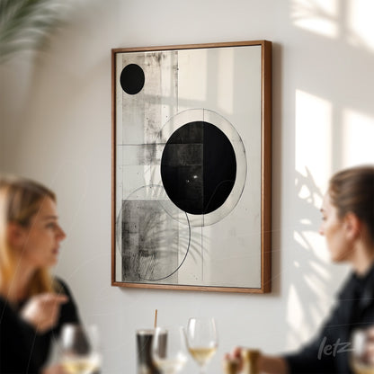 abstract wall art in wooden frame featuring geometric shapes in black and white displayed on light wall