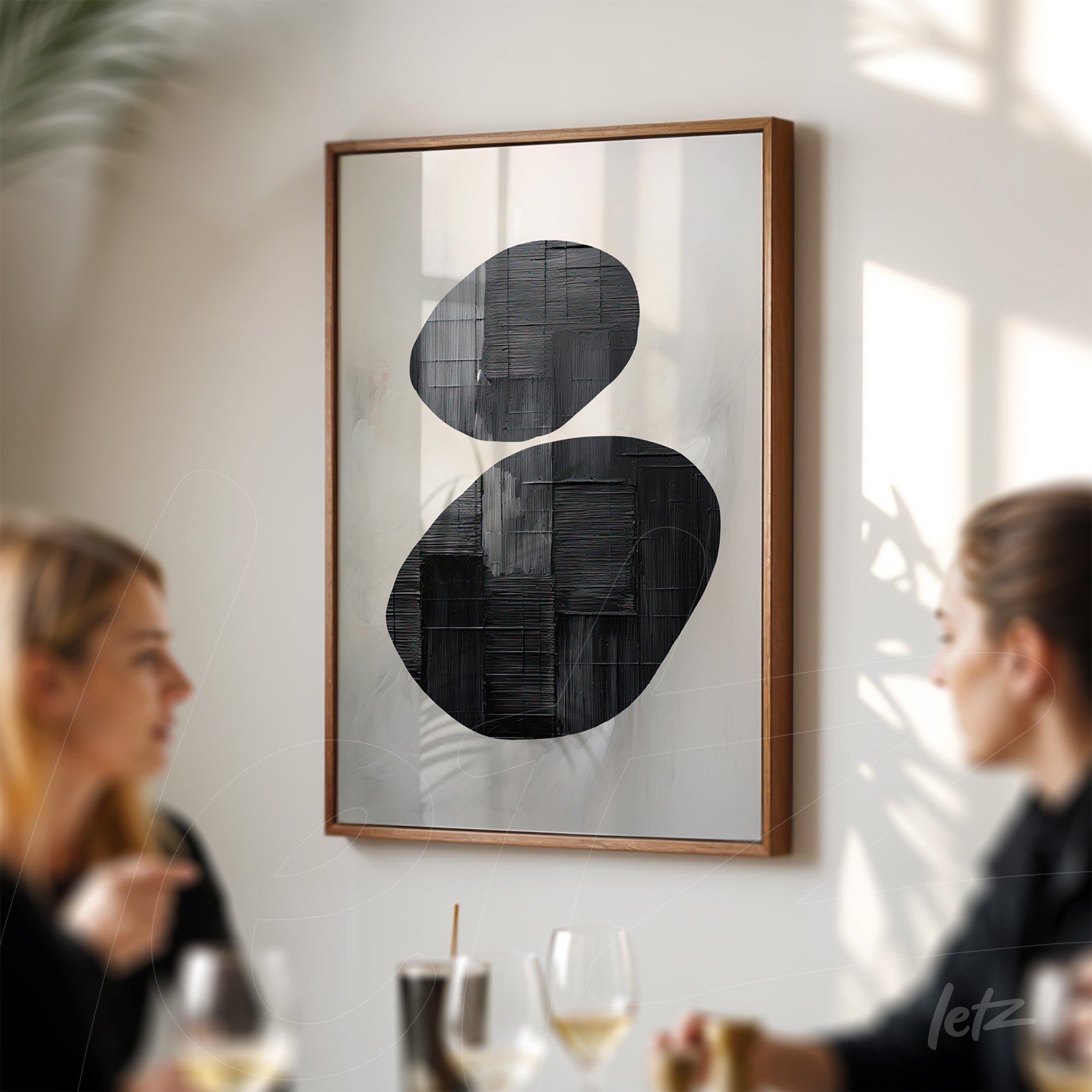 abstract framed wall art with black shapes on a light background displayed in a restaurant setting
