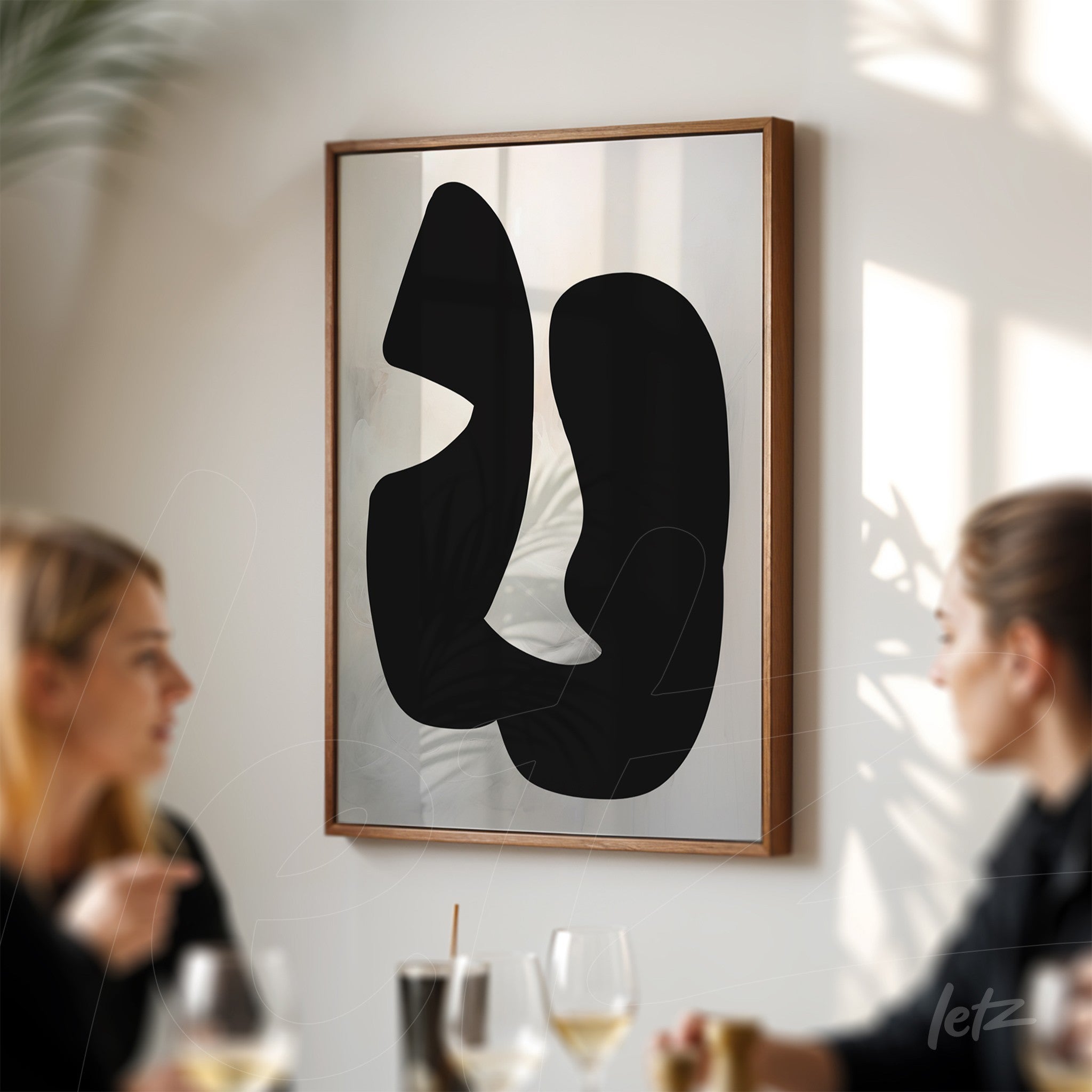 abstract art piece in black on a light background framed with a light wood frame displayed in a space with natural lighting