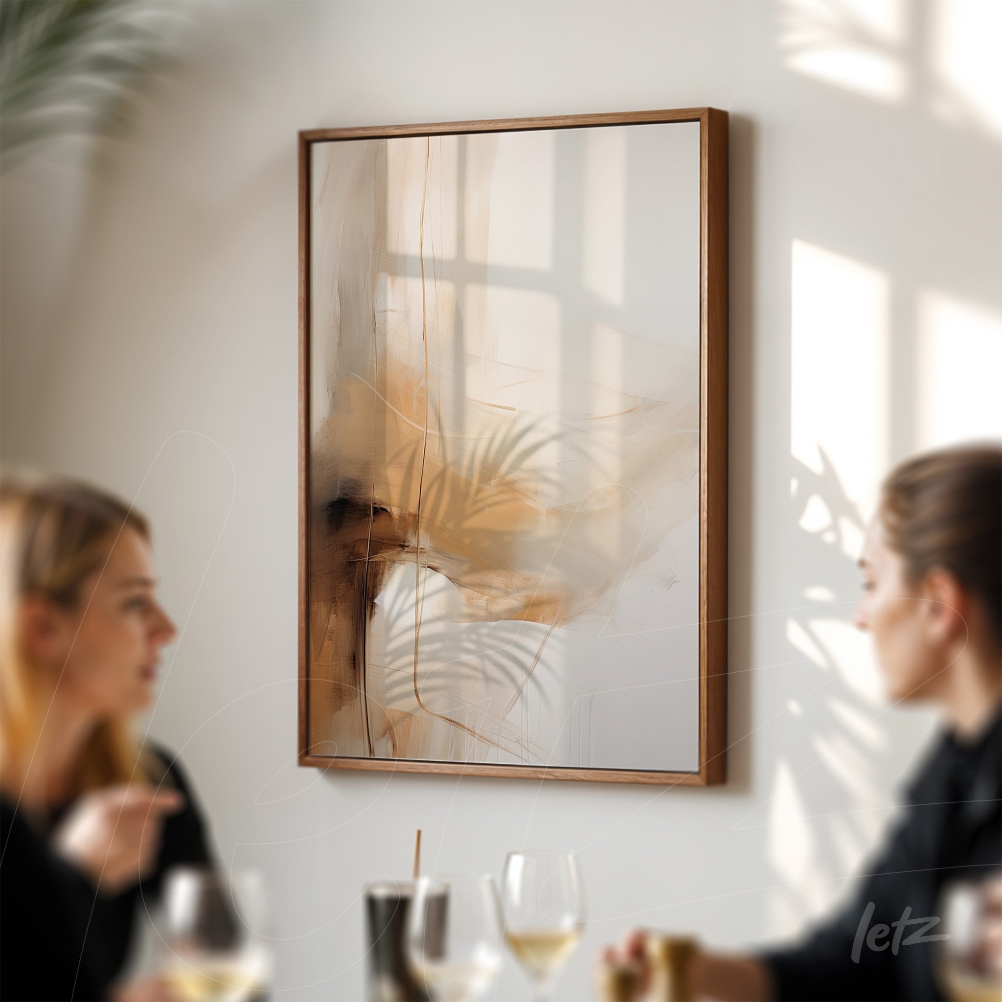abstract artwork with warm tones and foliage elements in light wood frame displayed on white wall