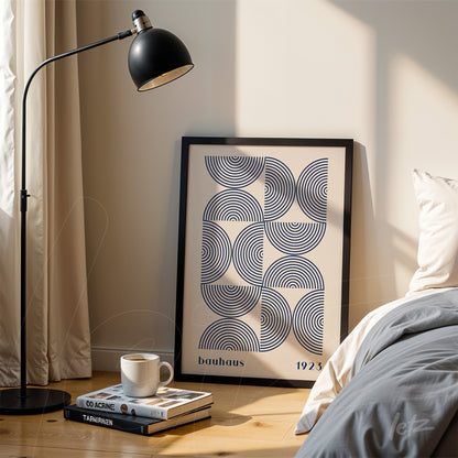 black framed geometric bauhaus style art leaning against the wall next to a bed