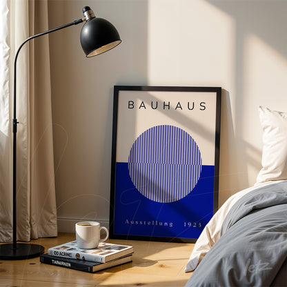 modern geometric Bauhaus style artwork in black frame, leaning on floor next to bed and lamp