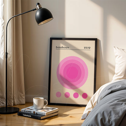 geometric art poster in shades of pink with the word 'bauhaus' in a black frame, leaning against a light-colored wall