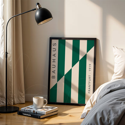 bauhaus style framed art with green and white diagonal stripes leaning against a wall near a bed