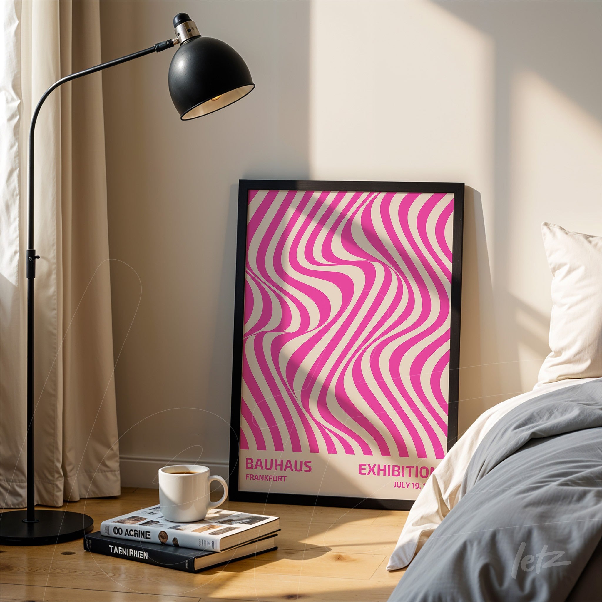 poster with abstract geometric design in pink and white in a black frame, leaning on the floor near a bed and reading lamp