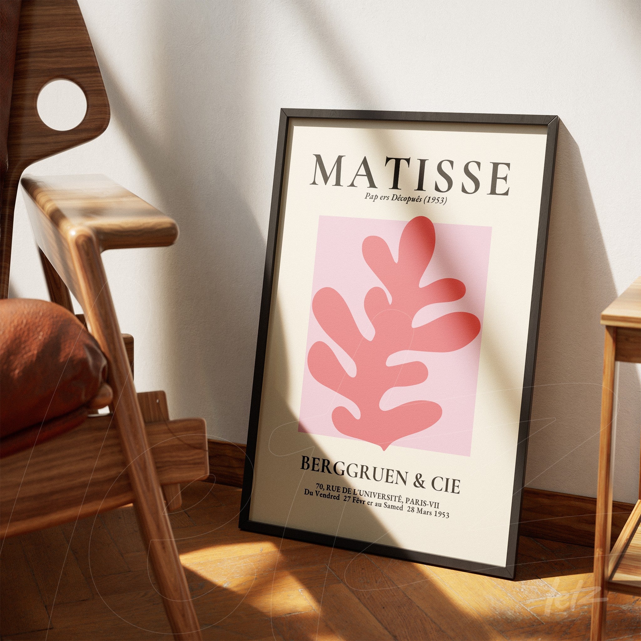 framed wall art featuring a minimalist pink leaf illustration, leaning against a wooden chair