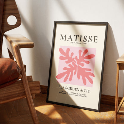 framed wall art featuring modern abstract shapes in shades of pink, leaning against a wooden floor