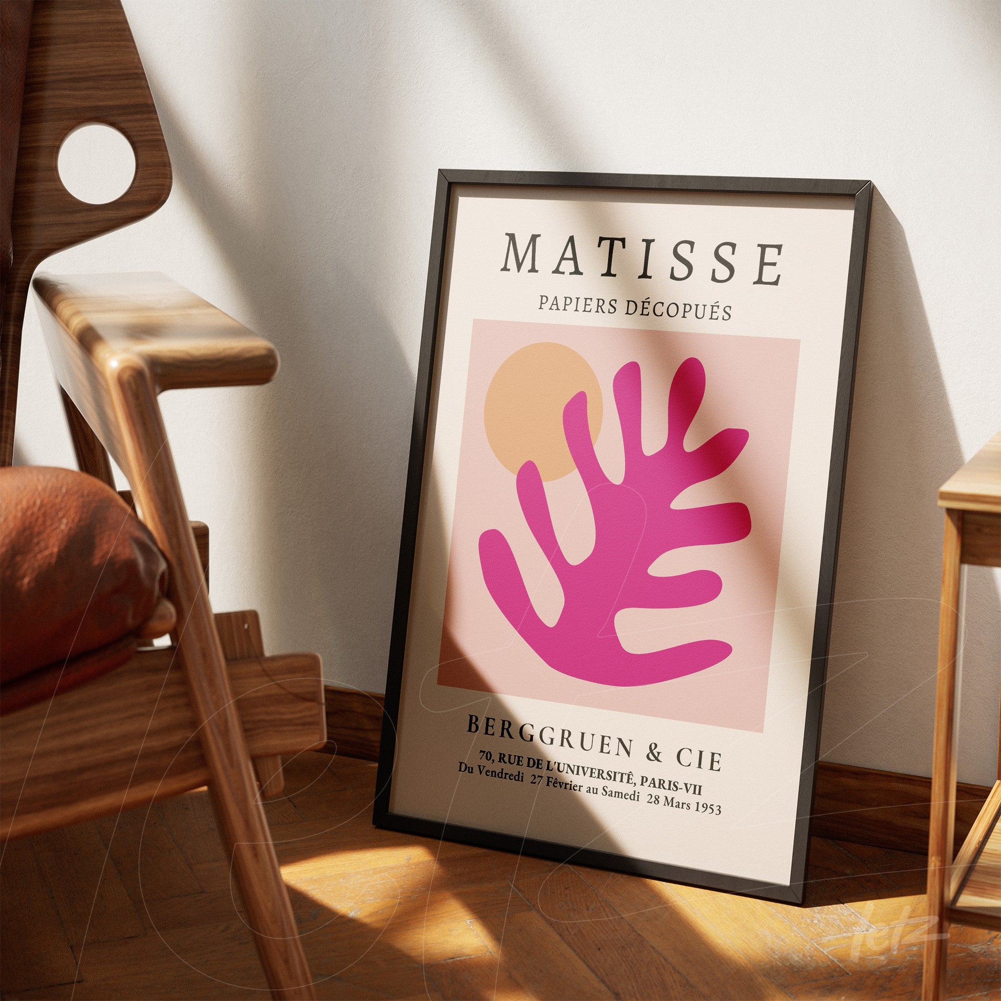 framed modern art piece featuring abstract shapes in pink and orange, leaning against a wooden chair