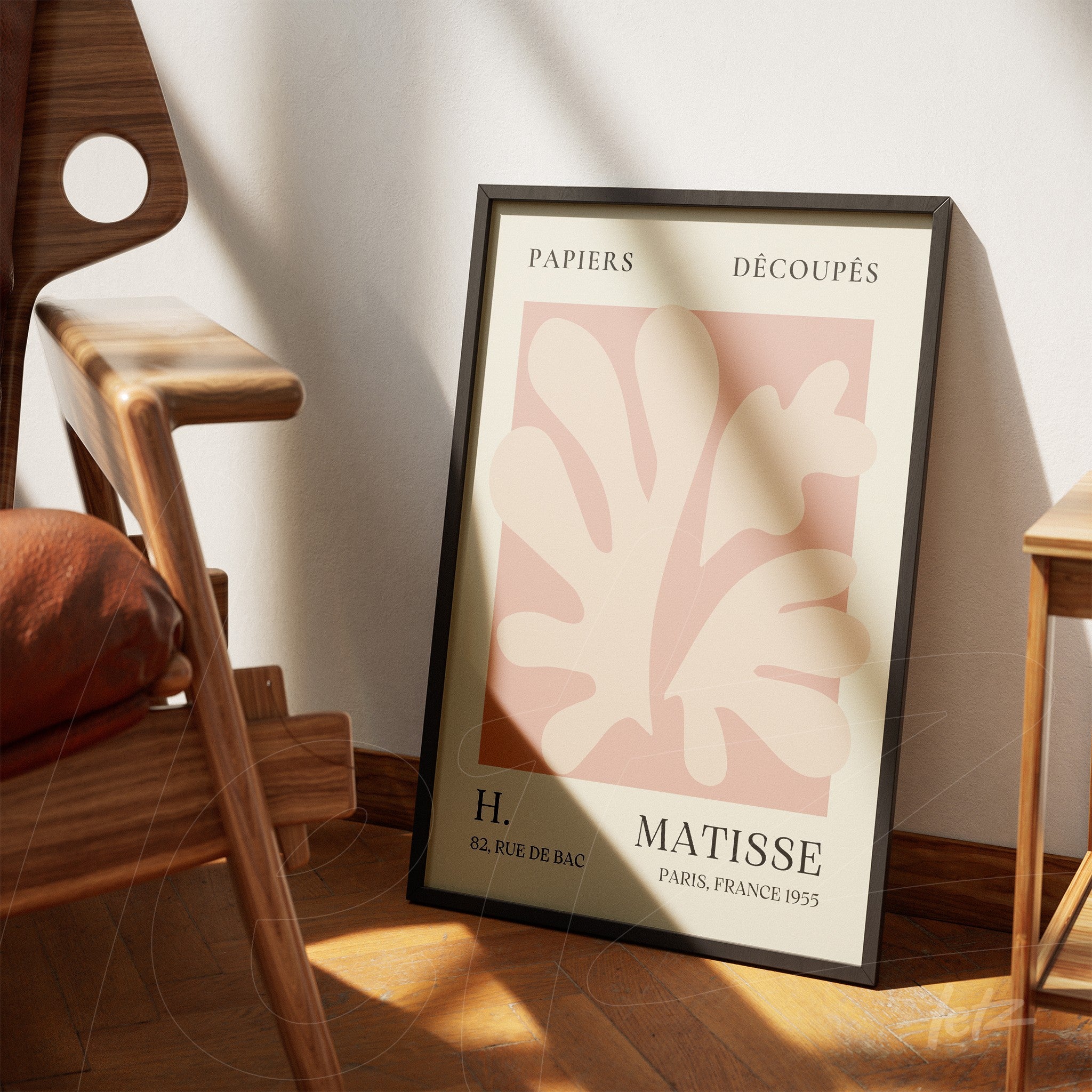 framed artwork in black showcasing paper cutouts in pink tones inspired by Matisse leaning beside a wooden chair