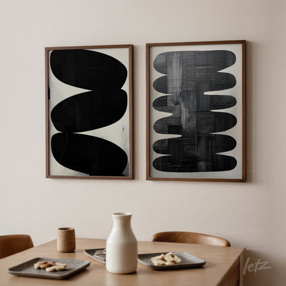 composition of two abstract wall art pieces in black and white with light wood frames displayed on a soft wall