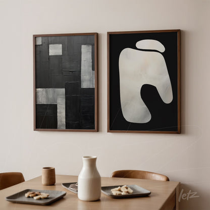 composition of abstract wall art in black and white, framed in light wood, displayed on a neutral wall in a cozy dining setting