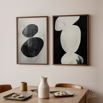 composition of abstract wall art in black and white with wooden frames displayed on a light wall