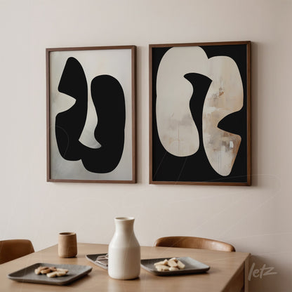composition of two abstract framed artworks, one with black shapes on light background and the other with light shapes on black background, displayed on a neutral wall