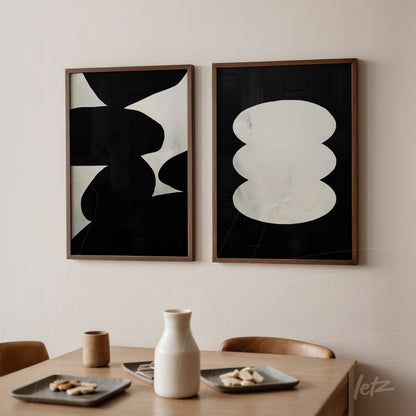 composition of abstract wall art in black and white with wooden frames displayed on a light wall