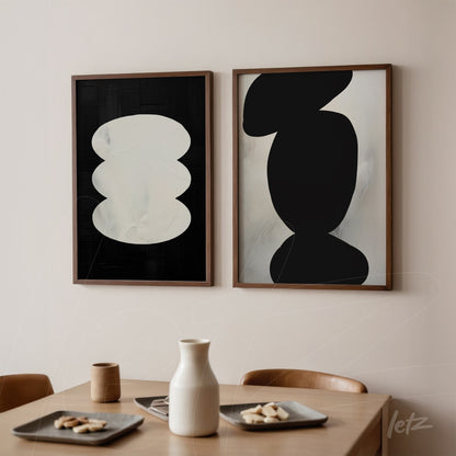 set of framed artworks featuring abstract black and white shapes in light wood frames displayed on a neutral wall