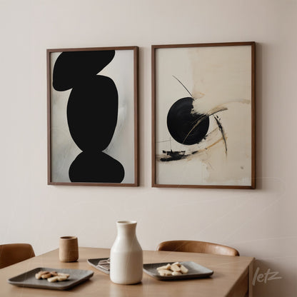 composition with two abstract framed artworks in natural wood frames, featuring a black shape in one piece and a neutral-toned design with a prominent black circle in the other