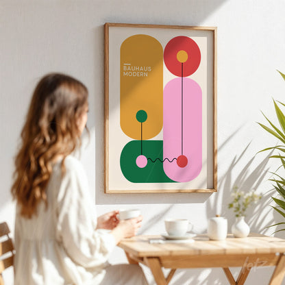 poster print featuring colorful geometric bauhaus-style design in a light wood frame, displayed on a white wall next to a table with cups