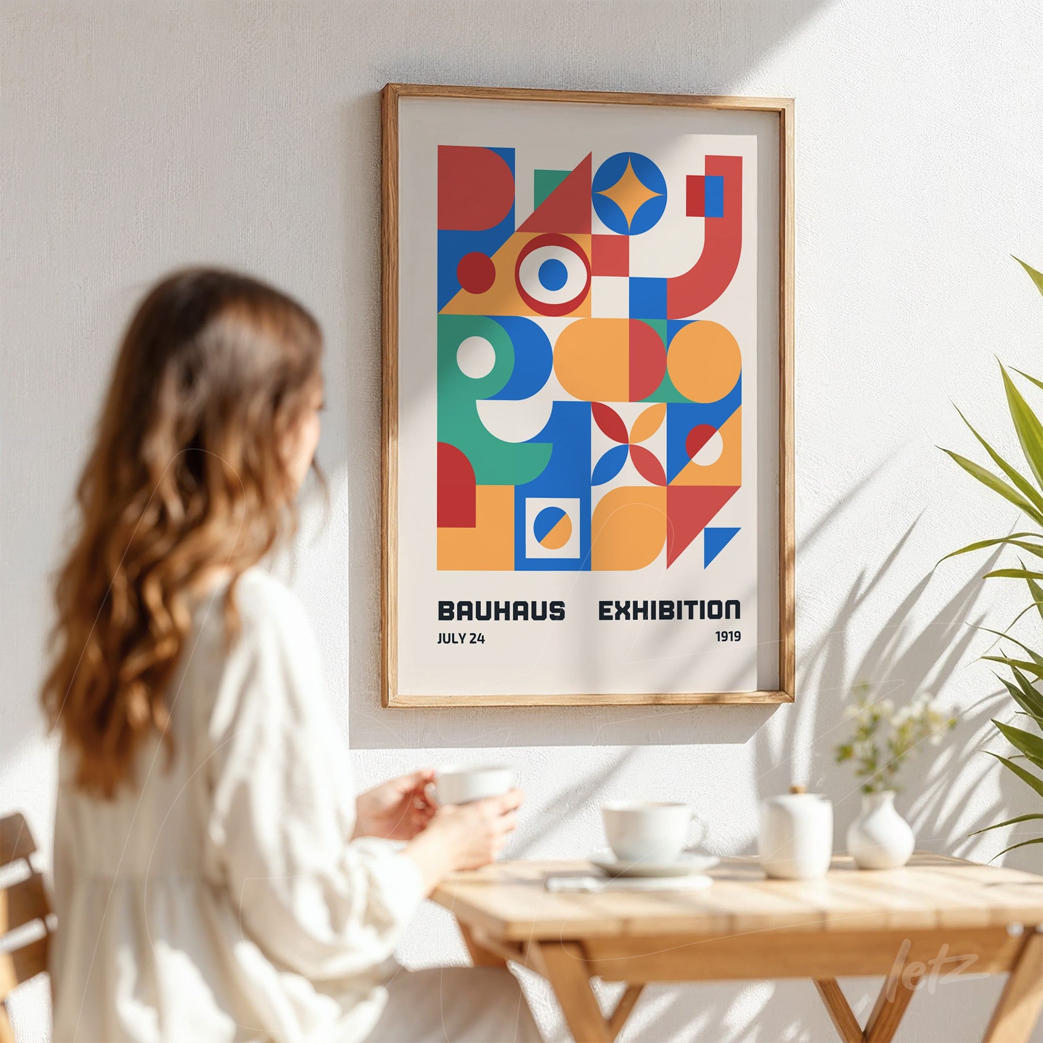 colorful bauhaus style poster with geometric shapes in light wood frame displayed on sunlit wall
