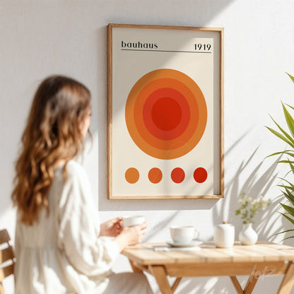 poster print featuring concentric circles in shades of orange displayed in a light wood frame on a white wall