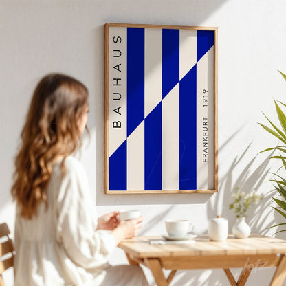modern art with blue and white stripes in a light wood frame, displayed on white wall