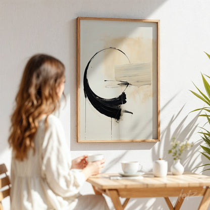 abstract art featuring black and cream brush strokes in a light wood frame displayed in a bright indoor setting