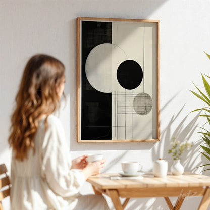 abstract wall art in black and white with light wood frame displayed on a white wall featuring large and small circles in geometric composition