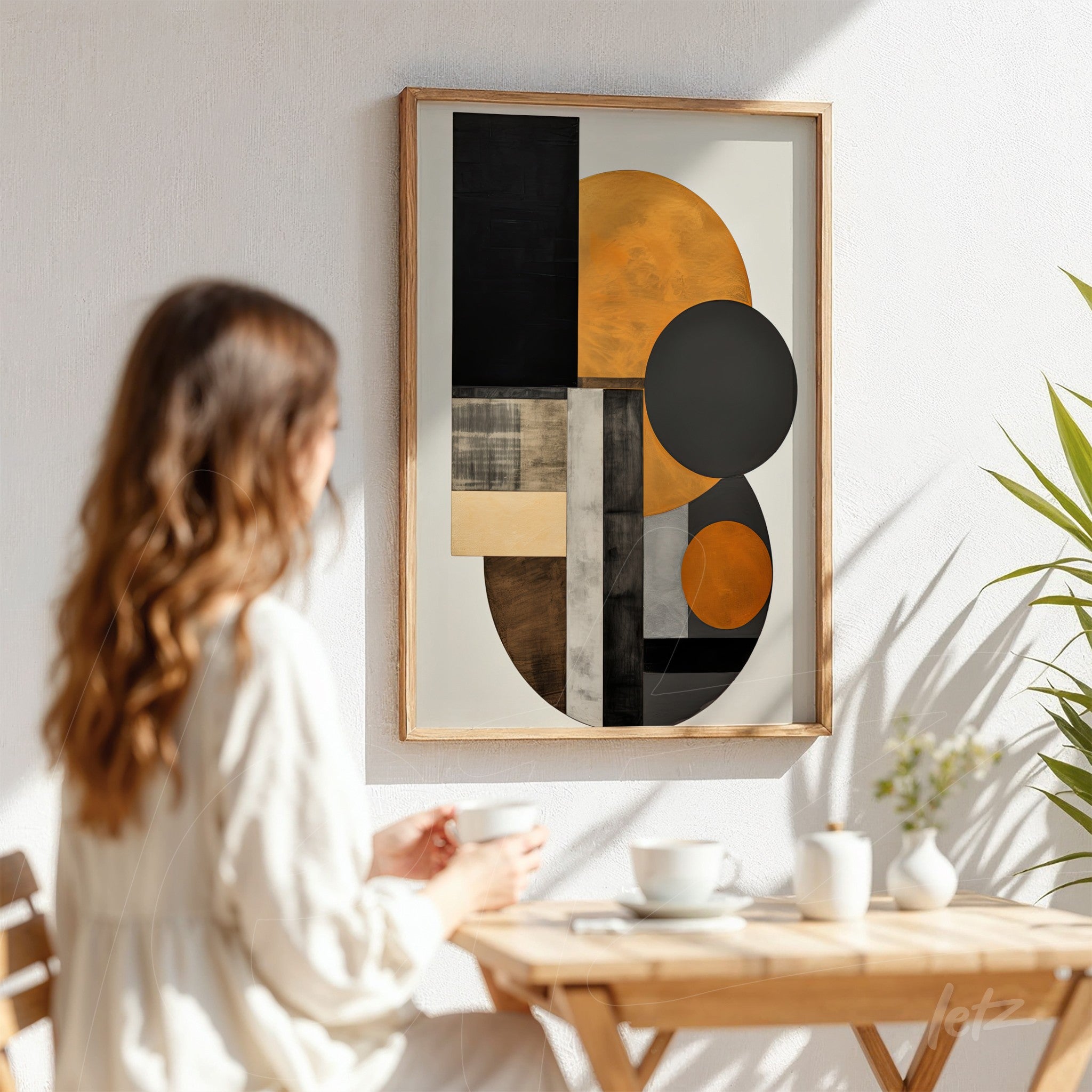 abstract artwork with geometric shapes in black, orange, and gray, framed in light wood, displayed on a wall with natural lighting