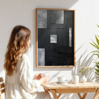 abstract wall art in shades of black and gray with light wooden frame displayed on white wall