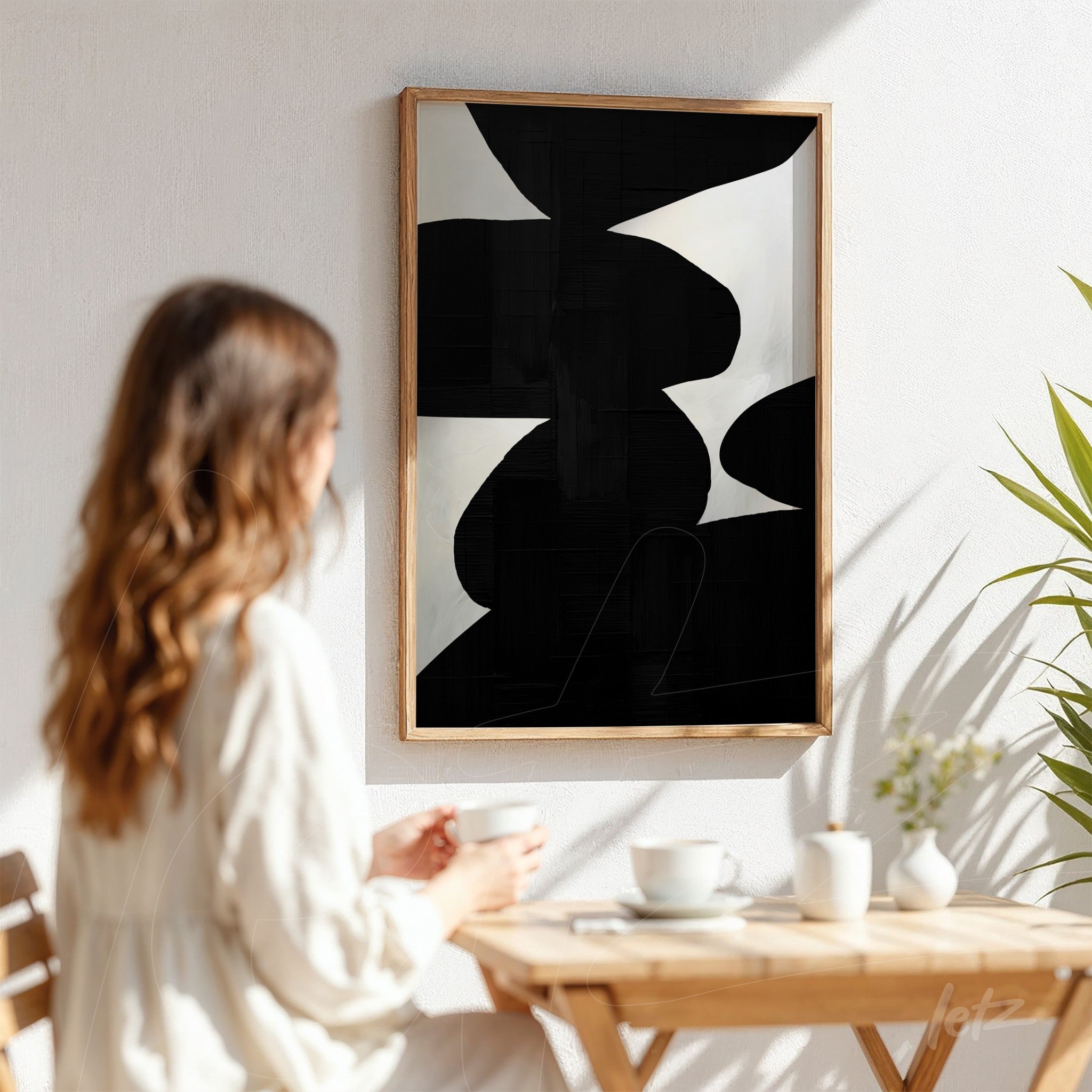 abstract wall art in black and white with light wooden frame displayed on light wall