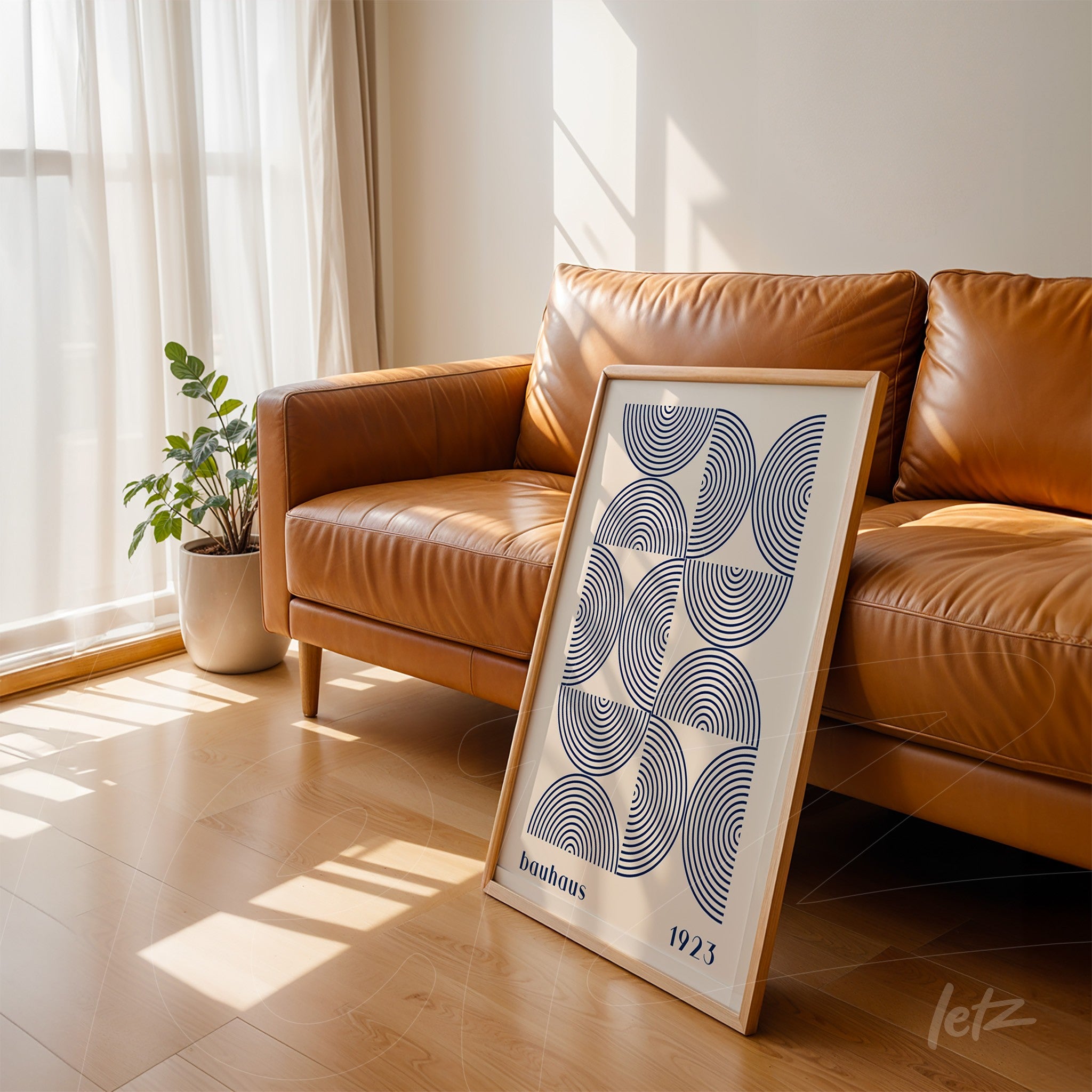 geometric art with black and white concentric circles, light wooden frame, leaning against caramel leather sofa