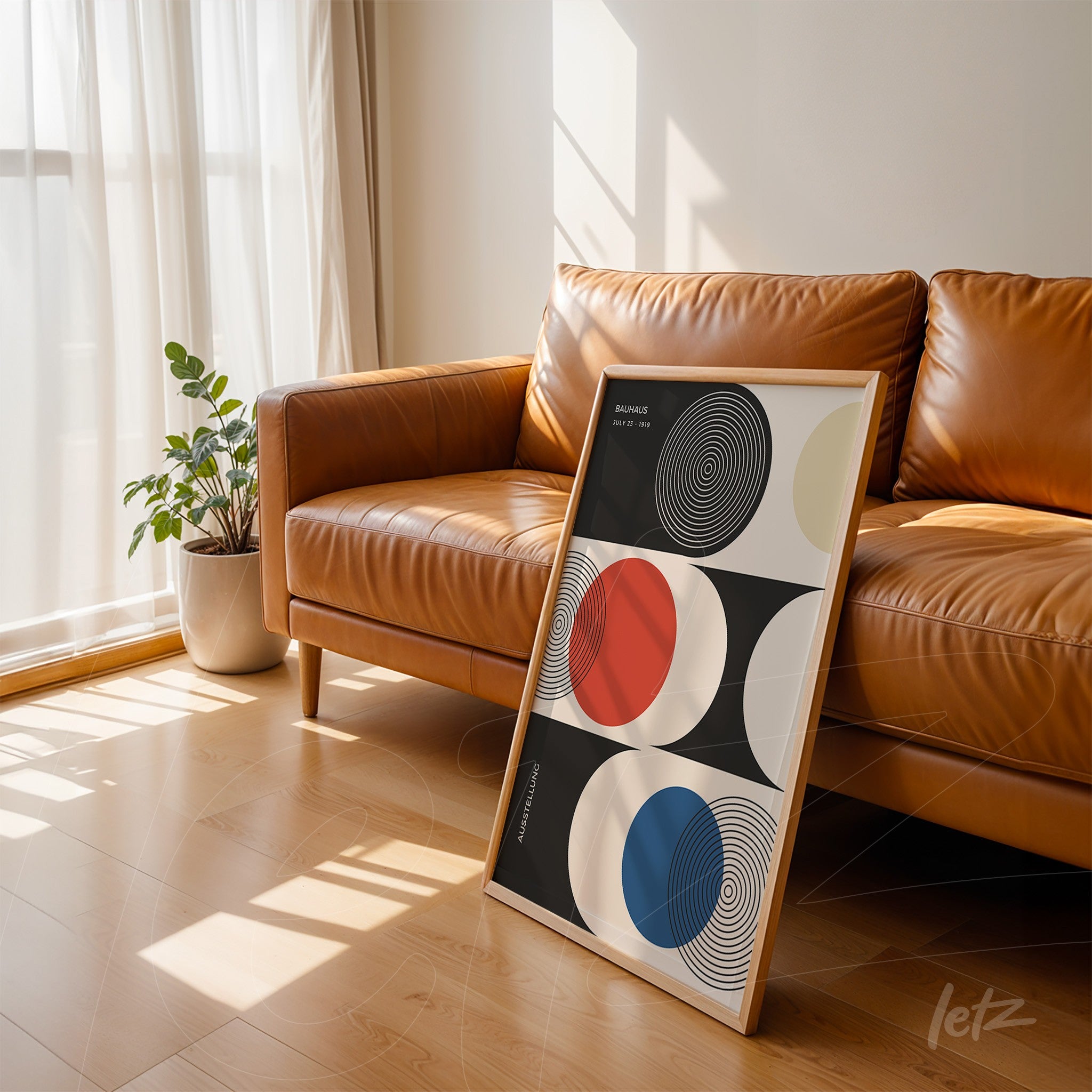 modern geometric art in wooden frame leaning on brown leather sofa in a sunlit room