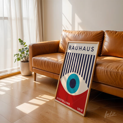 poster print featuring Bauhaus geometric design displayed in light wood frame leaning against a leather sofa