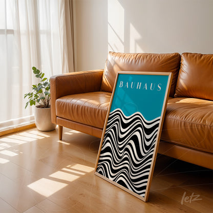 modern framed art with black and white waves, bauhaus text on blue, leaning against brown leather sofa
