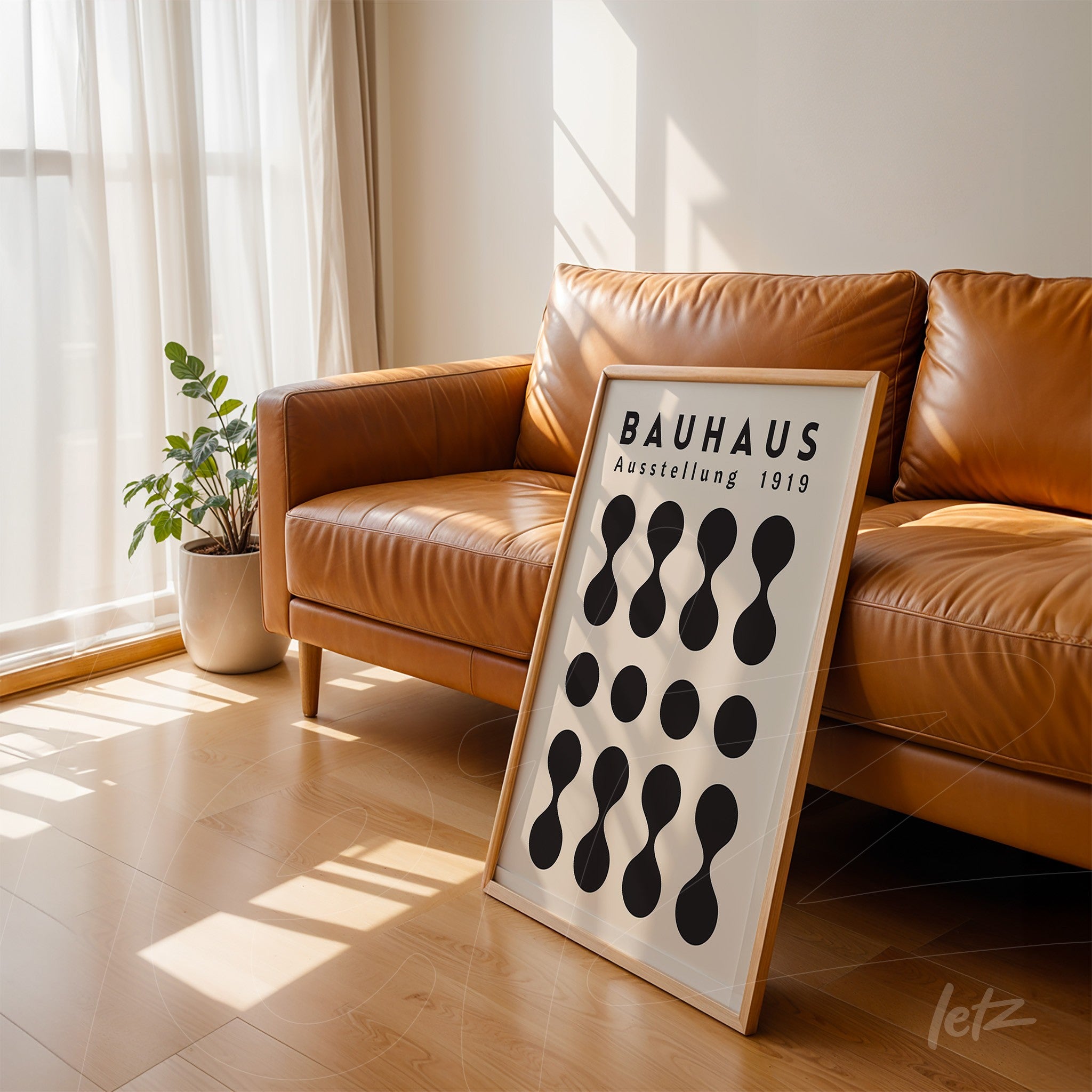 black and white geometric Bauhaus inspired poster leaning against a brown leather sofa in a well-lit living room