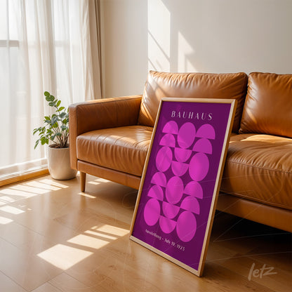 poster print displayed on wooden floor next to brown couch, featuring geometric art in purple tones with light wood frame