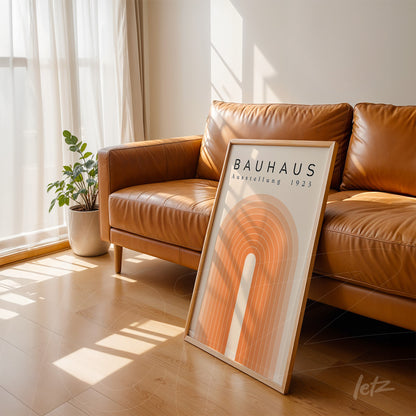 poster print with bauhaus-style geometric design in orange hues, leaning on leather sofa in sunlit room