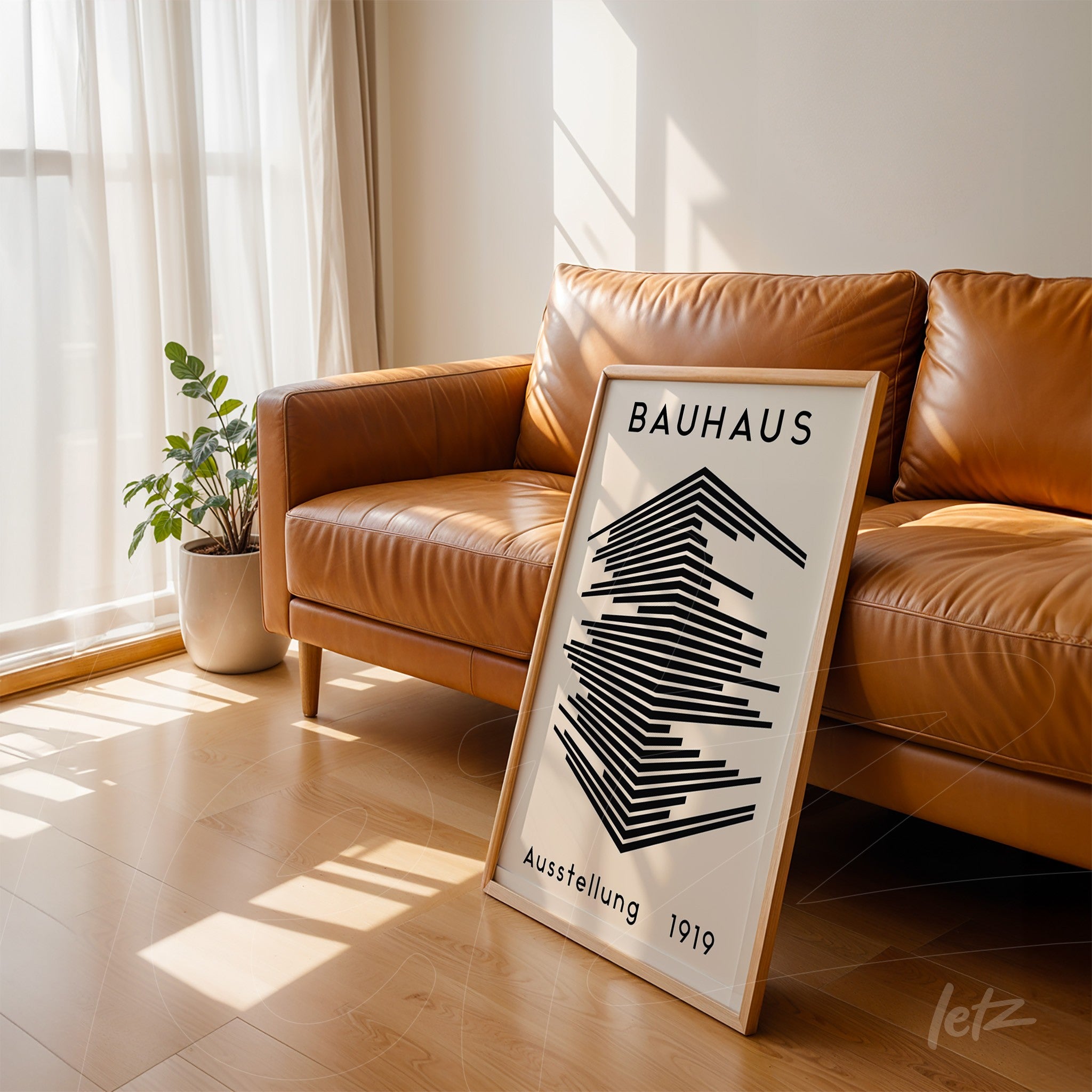 black and white geometric Bauhaus style poster leaning against brown leather sofa