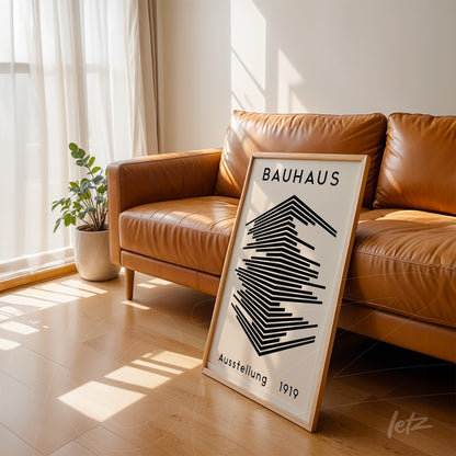 black and white geometric Bauhaus style poster leaning against brown leather sofa